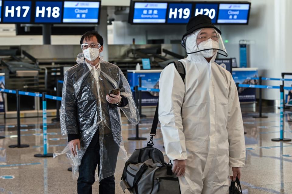 Passengers wearing protective gear walk at the Tianhe Airport after it was reopened, in Wuhan in China's central Hubei province on April 8, 2020. - Thousands of Chinese travellers rushed to leave COVID-19 coronavirus-ravaged Wuhan on April 8 as authorities lifted a more than two-month prohibition on outbound travel from the city where the global pandemic first emerged. (Photo by Hector RETAMAL / AFP) (Photo by HECTOR RETAMAL/AFP via Getty Images)