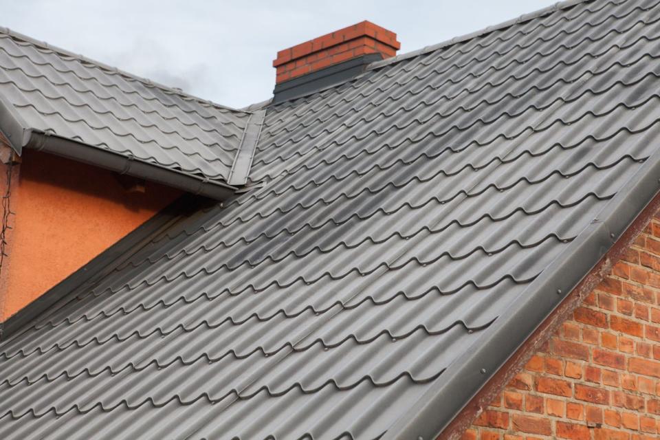 Black roof made of sheet metal in winter, frost on the roof