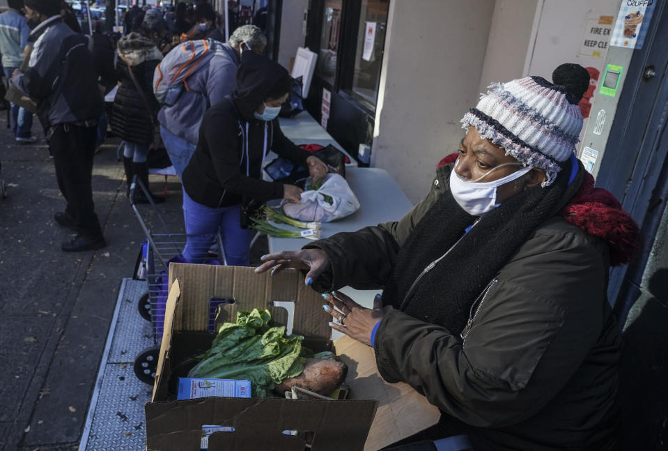 Gloria Robinson, right, pack the last of items of food received at Harlem's Food Bank For New York City, a community kitchen and food pantry, Monday, Nov. 16, 2020, in New York. Robinson, who traveled from the nearby Bronx, said "this is going to help a whole lot. I so appreciate it, I'm so happy right now." (AP Photo/Bebeto Matthews)