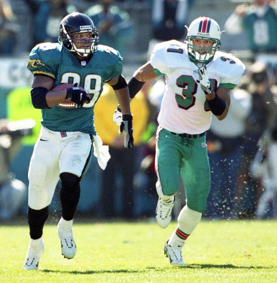 Jaguars running back Fred Taylor, seen here eluding Miami Dolphins' safety Brock Marion (31) in a 62-7 Jaguars' rout during a 1999 AFC playoff game at TIAA Bank Field, has more rushing yards than any player currently eligible for the Pro Football Hall of Fame.