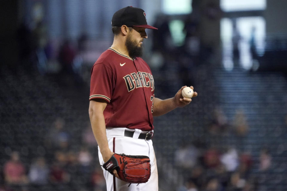 Arizona Diamondbacks starting pitcher Caleb Smith looks at the baseball after giving up a run against the Milwaukee Brewers during the XXX inning of a baseball game, Wednesday, June 23, 2021, in Phoenix. (AP Photo/Matt York)