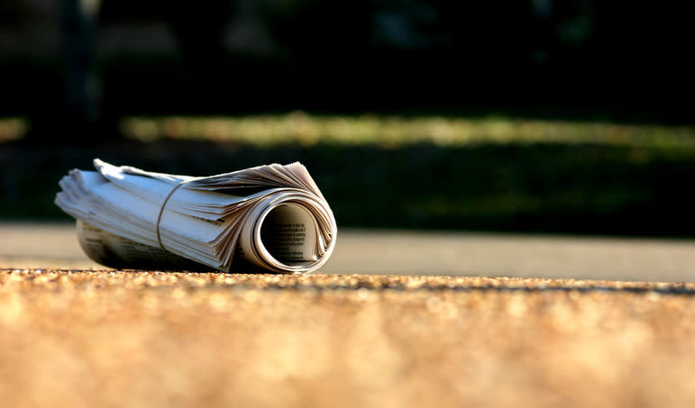 Rolled-up newspaper on a driveway, symbolizing a family's morning routine