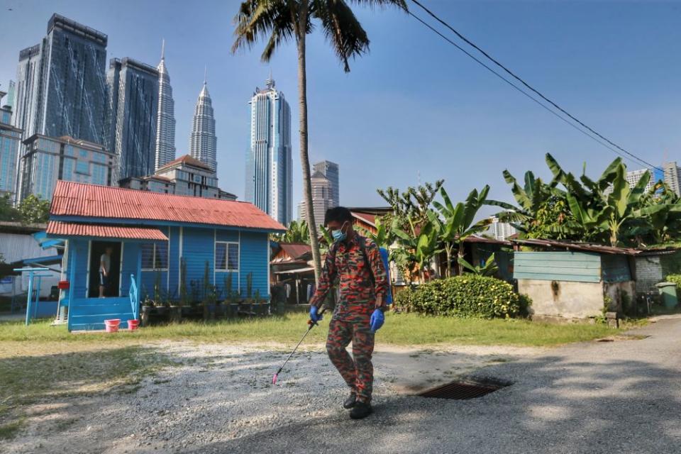 A Fire and Rescue personnel sprays disinfectant in Kampung Baru to curb spread of Covid-19 in Kuala Lumpur March 31, 2020. — Picture by Ahmad Zamzahuri