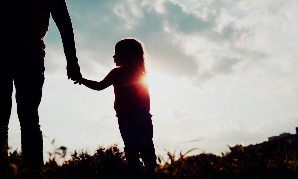 Silhouette of a little girl holding her parent's hand