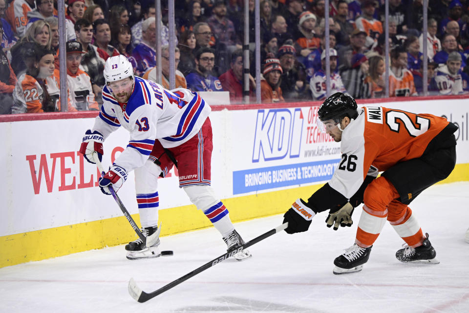 New York Rangers' Alexis Lafreniere, left, plays the puck past Philadelphia Flyers' Sean Walker (26) during the first period of an NHL hockey game, Saturday, Feb. 24, 2024, in Philadelphia. (AP Photo/Derik Hamilton)