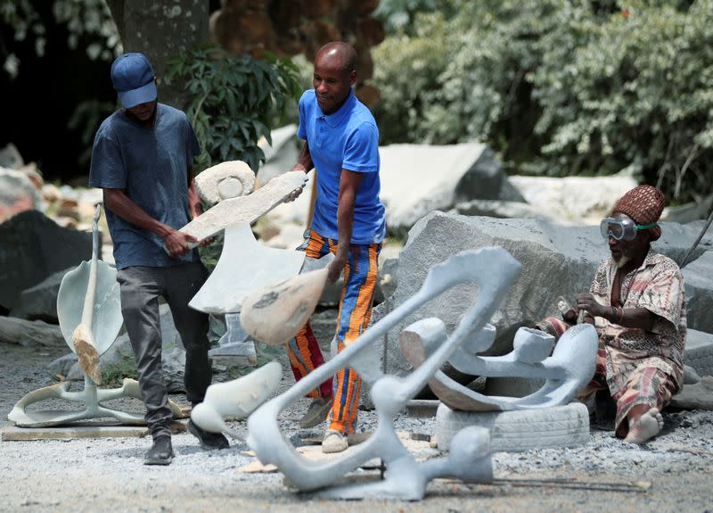 Zimbabwean sculptor Dominic Benhura carries a finished piece at his studio in Harare