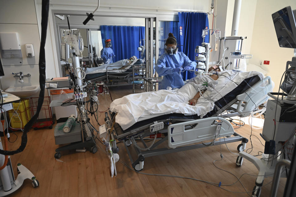 Members of the clinical staff wearing Personal Protective Equipment PPE care for a patient with coronavirus in the intensive care unit at the Royal Papworth Hospital in Cambridge, England, Tuesday May 5, 2020. (Neil Hall/Pool via AP)