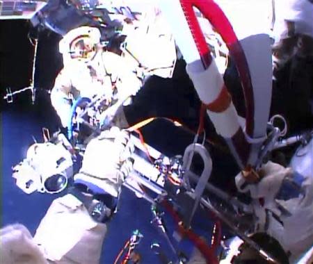 Russian astronaut Oleg Kotov holds an Olympic torch as he takes it on a spacewalk as Russian astronaut Sergei Ryazansky prepares the camera outside the International Space Station in this still image taken from video courtesy of NASA TV, November 9, 2013. REUTERS/NASA TV/Handout via Reuters