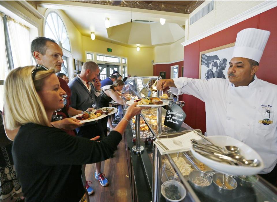 This photo taken on Wednesday, June 5, 2013 shows tourists receiving a gourmet lunch on their Universal Studios Hollywood's “VIP Experience,” a $299 per person ticket that includes a private trolley, lunch, a VIP lounge, and amenities. Many theme parks now have VIP tours with perks usually reserved for celebrities _ private tour guides, no waits for the biggest attractions, reserved seating at shows and parades along with behind-the-scenes peaks at places normally off limits. (AP Photo/Damian Dovarganes)