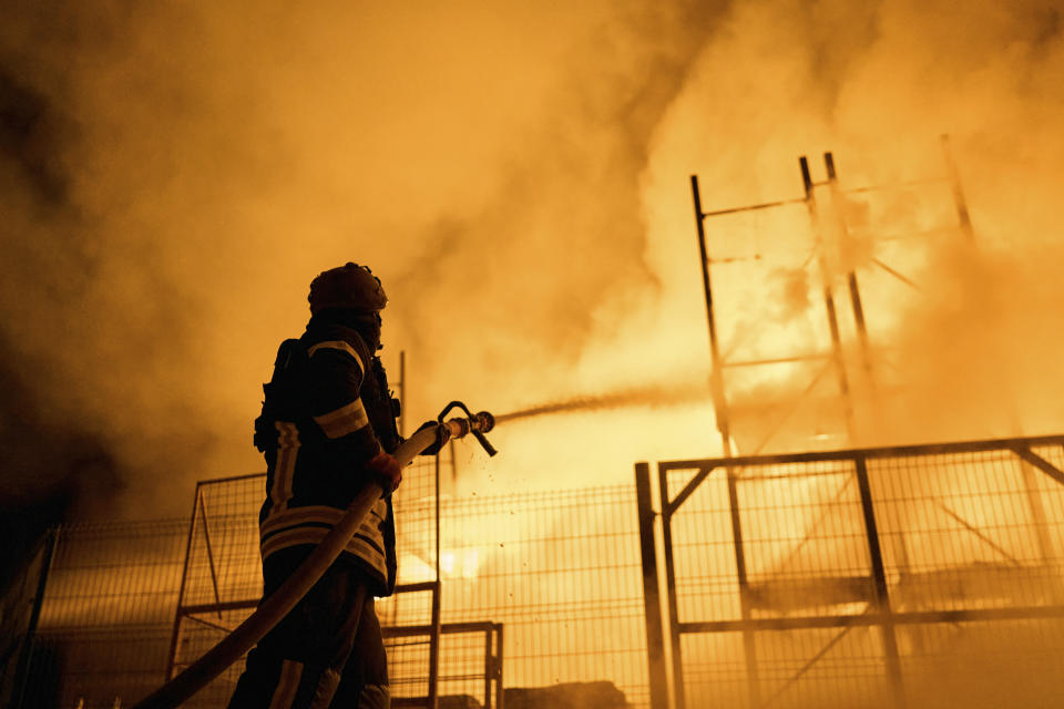 A Ukrainian State Emergency Service firefighter puts out a fire after Russian shelling hit a shopping center in Kherson, Ukraine, Friday, Feb. 3, 2023. (AP Photo/LIBKOS)