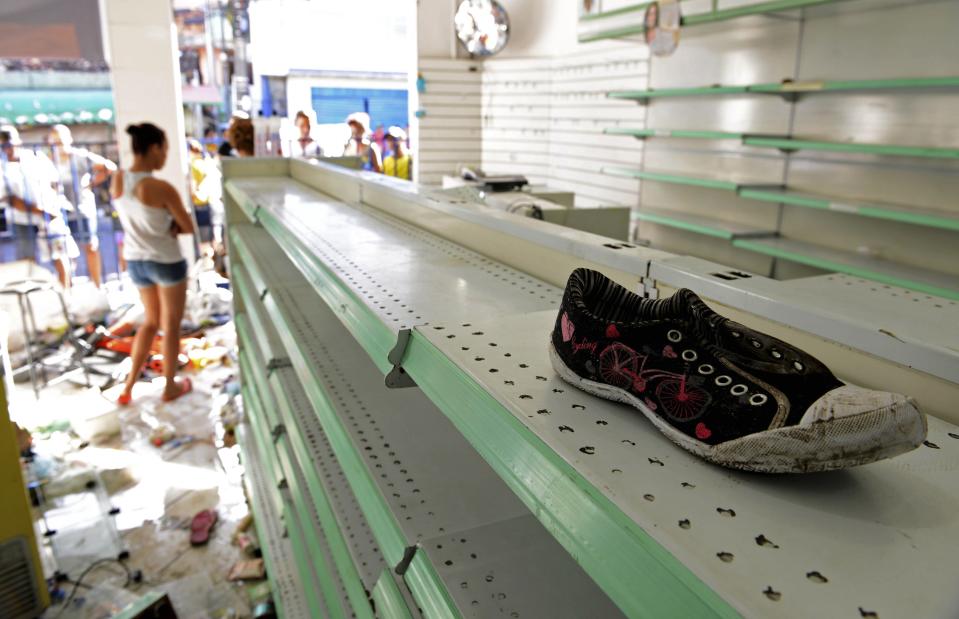 A woman stands inside a store that was looted during a police strike in Salvador