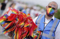 A man offers LGBT pride flags to football supporters outside of the stadium before the Euro 2020 soccer championship group F match between Germany and Hungary at the Allianz Arena in Munich, Germany,Wednesday, June 23, 2021. (AP Photo/Matthias Schrader)