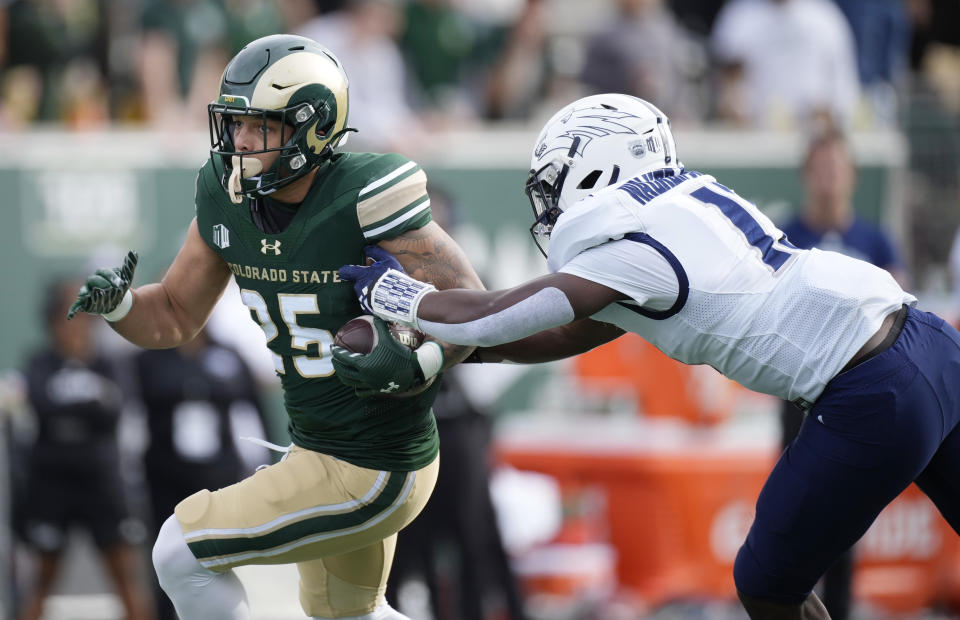 Colorado State running back Avery Morrow, left, runs for a short gain as Nevada linebacker Marcel Walker-Burgess defends in the first half of an NCAA college football game Saturday, Nov. 18, 2023, in Fort Collins, Colo. (AP Photo/David Zalubowski)