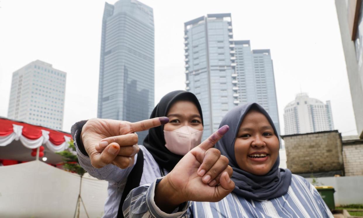 <span>Two women show their ink-marked fingers after casting their votes in Jakarta.</span><span>Photograph: Bagus Indahono/EPA</span>