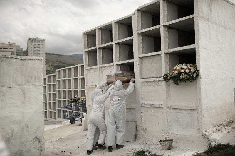 Cemetery workers place the coffin containing the remains of Jose de Arimateia, 65, who died from COVID-19 complications, into a niche at the municipal cemetery in Nova Iguacu, Brazil.