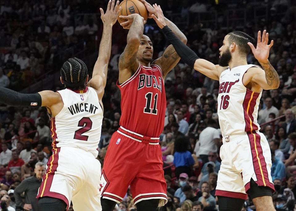 Miami Heat guard Gabe Vincent (2) and forward Caleb Martin (16) pressure Chicago Bulls center DeMar DeRozan (11) during the first half of an NBA basketball game Monday, Feb. 28, 2022, in Miami. (AP Photo/Marta Lavandier)