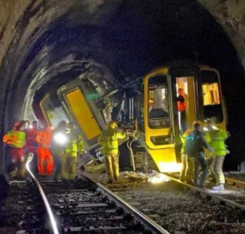 急救人員在隧道內使用手電筒引導乘客沿著軌道。