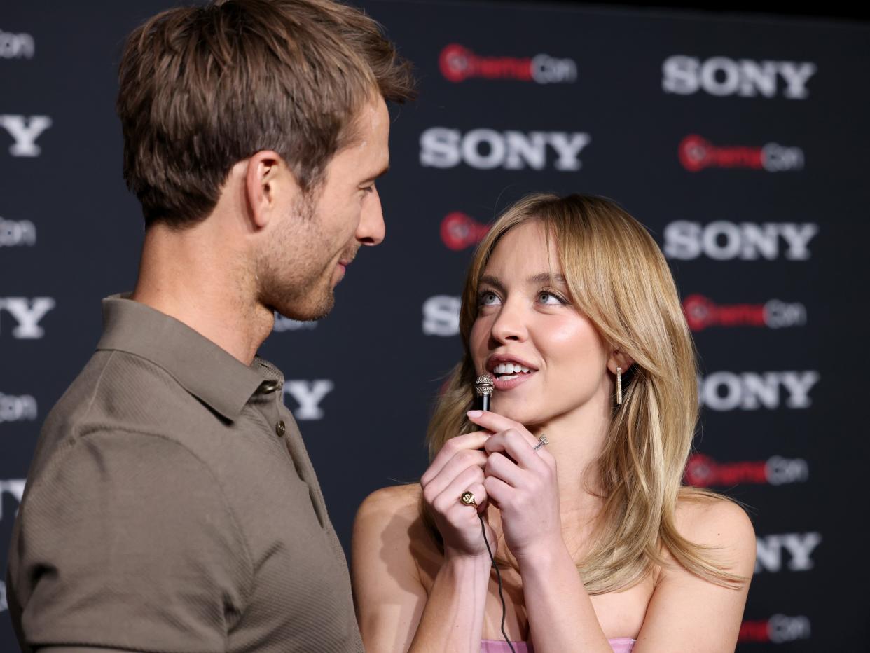 Glen Powell and Sydney Sweeney interviewing one another with a mini-microphone at CinemaCon.