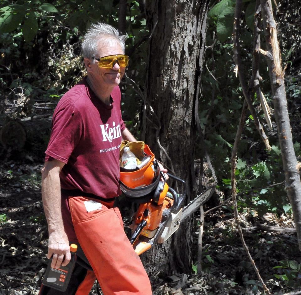 Paul Harkinst heads to the backyard with a chainsaw and safety equipment.