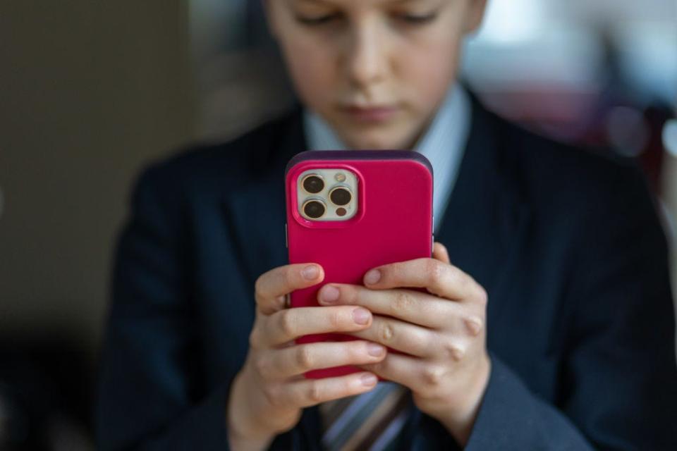 A young boy holding a red cellphone.