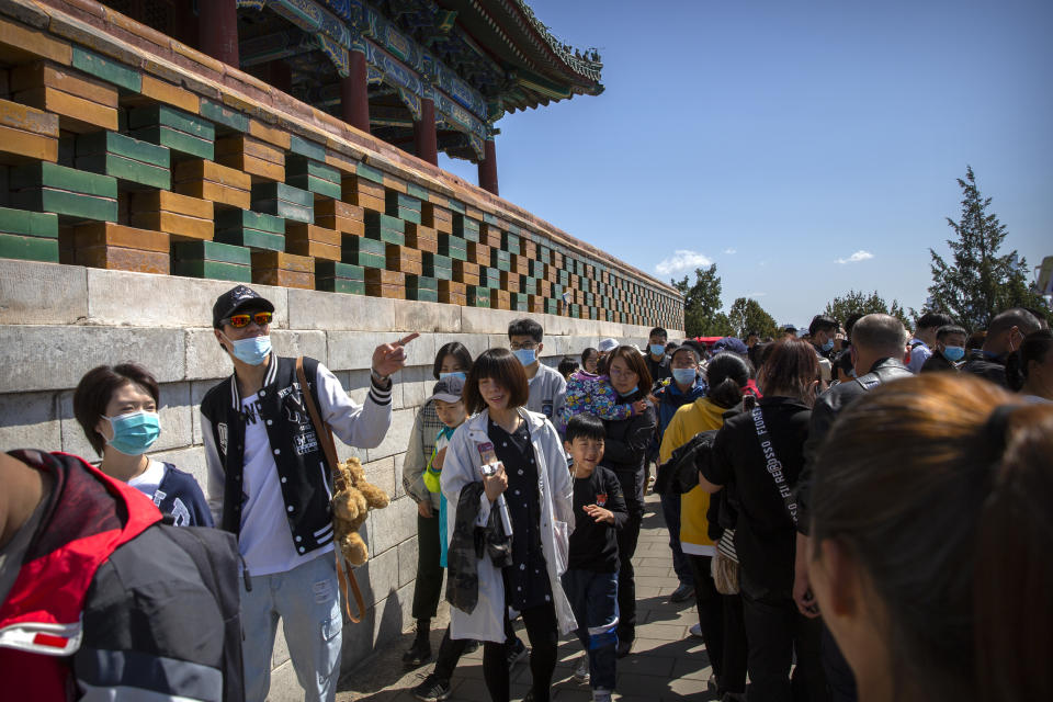 Visitors wearing face masks gather at a viewing area overlooking the Forbidden City at a public park in Beijing, Saturday, May 1, 2021. Chinese tourists are expected to make a total of 18.3 million railway passenger trips on the first day of the country's five-day holiday for international labor day, according to an estimate by the state railway group, as tourists rush to travel domestically after the coronavirus has been brought under control in China.(AP Photo/Mark Schiefelbein)