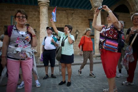 A tour guide (C) raises a Cuban national flag to regroup foreign visitors she is taking through Old Havana March 16, 2016. REUTERS/Alexandre Meneghini