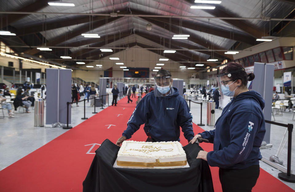 A cake is rolled out to celebrate the nursing students for the class of 2021, so they can gather around the cake during a mini celebration at the Downsview Arena vaccination site, in Toronto, Friday, April 16, 2021. (Tijana Martin/The Canadian Press via AP)