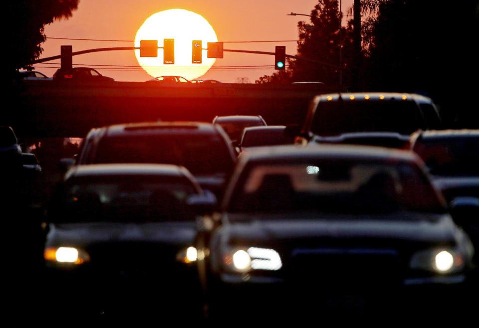 Traffic stacks up in Long Beach as a glowing-orange sun sets.