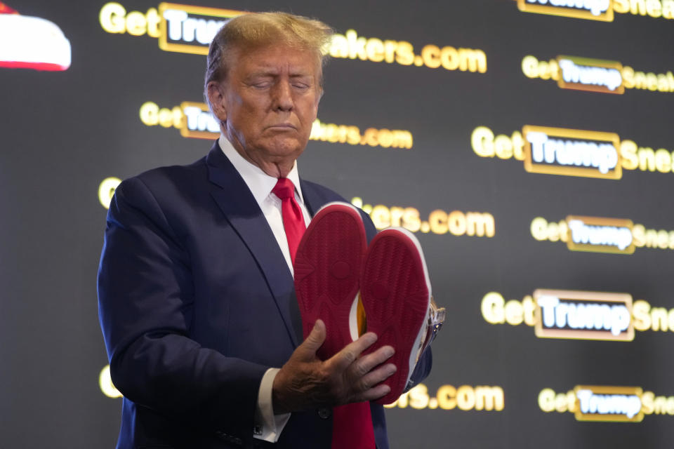 Republican presidential candidate former President Donald Trump looks at gold Trump sneakers at Sneaker Con Philadelphia, an event popular among sneaker collectors, in Philadelphia, Saturday, Feb. 17, 2024. (AP Photo/Manuel Balce Ceneta)