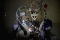 Nubia Rocio Gaona, 37, center, her sons, David, 14, right, and Jeimmer, 9, are reflected in a mirror during breakfast, at their home in Chipaque, Colombia, Saturday, May 9, 2020. The small-time farming mother and two sons are reinventing themselves as YouTubers due to a quarantine ordered by the government to contain the spread of COVID-19, teaching others how to grow vegetables at home and providing self-starter kits that they deliver through a local courier. (AP Photo/Fernando Vergara)