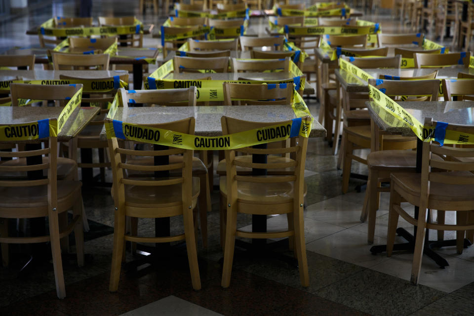 Un precinto de cinta amarilla rodea mesas y sillas en una zona de restaurantes para evitar que se usen los comedores interiores durante la pandemia del coronavirus, en Koreatown, Los Ángeles, el 8 de julio de 2020. (AP Foto/Jae C. Hong)