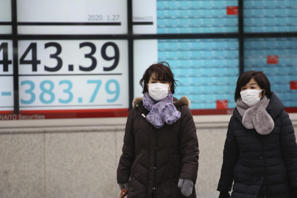 People walk by an electronic stock board of a securities firm in Tokyo, Monday, Jan. 27, 2020. Shares tumbled Monday in the few Asian markets open as China announced sharp increases in the number of people affected in an outbreak of a potentially deadly virus. (AP Photo/Koji Sasahara)