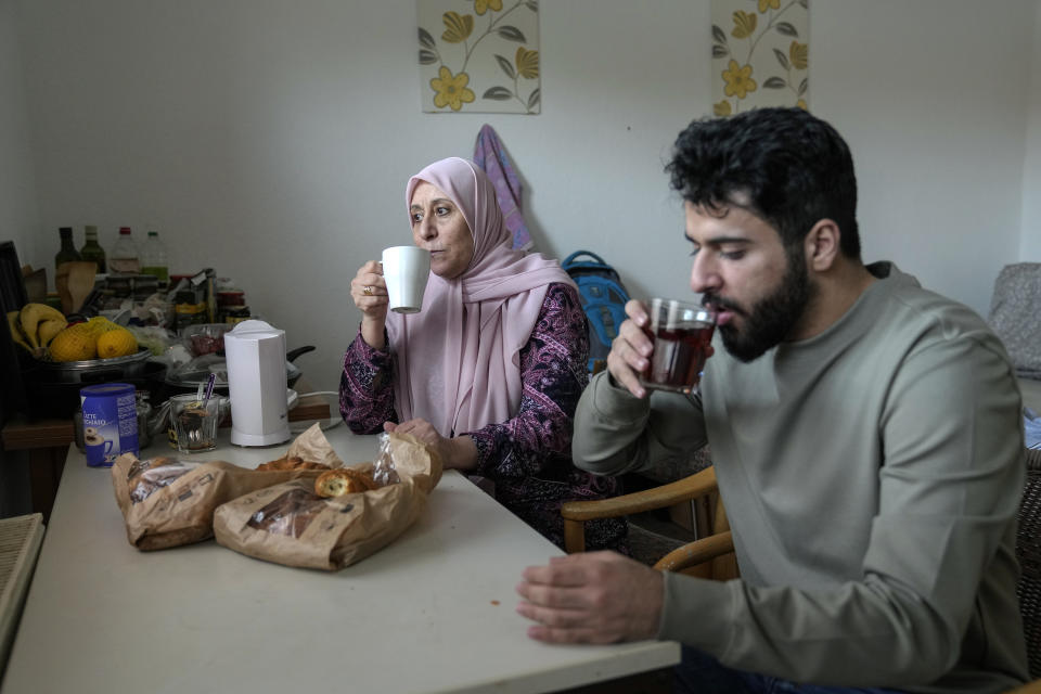 Palestinian asylum seekers Jihad Ammuri 20-year-old and his mother amileh Saqer 68-year-old, drink tea in a refugee shelter, in Eichsfeld, Germany, Wednesday, April 24, 2024. Across Germany, cities and counties are introducing new payment cards for asylum-seekers. The new rule, which was passed by parliament last month, calls for the migrants to receive their benefits on a card that can be used for payments in local shops and services. (AP Photo/Ebrahim Noroozi)