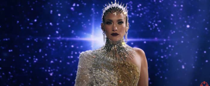 J Lo wearing a one-sleeved sequined costume with matching headpiece