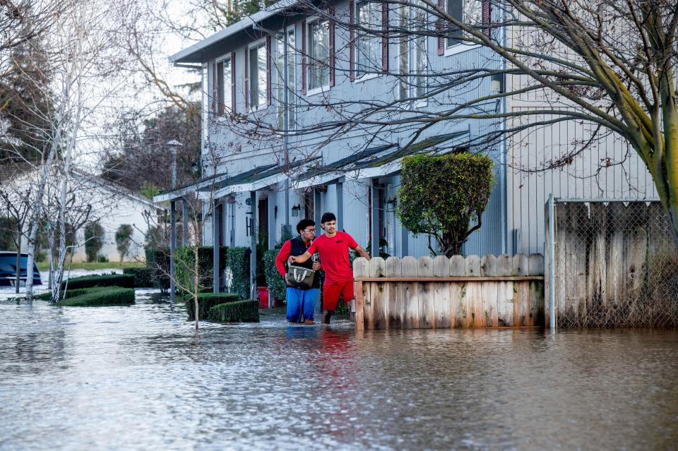 Abraham Ayala, right, wades through water in Merced, Calif., on Tuesday.