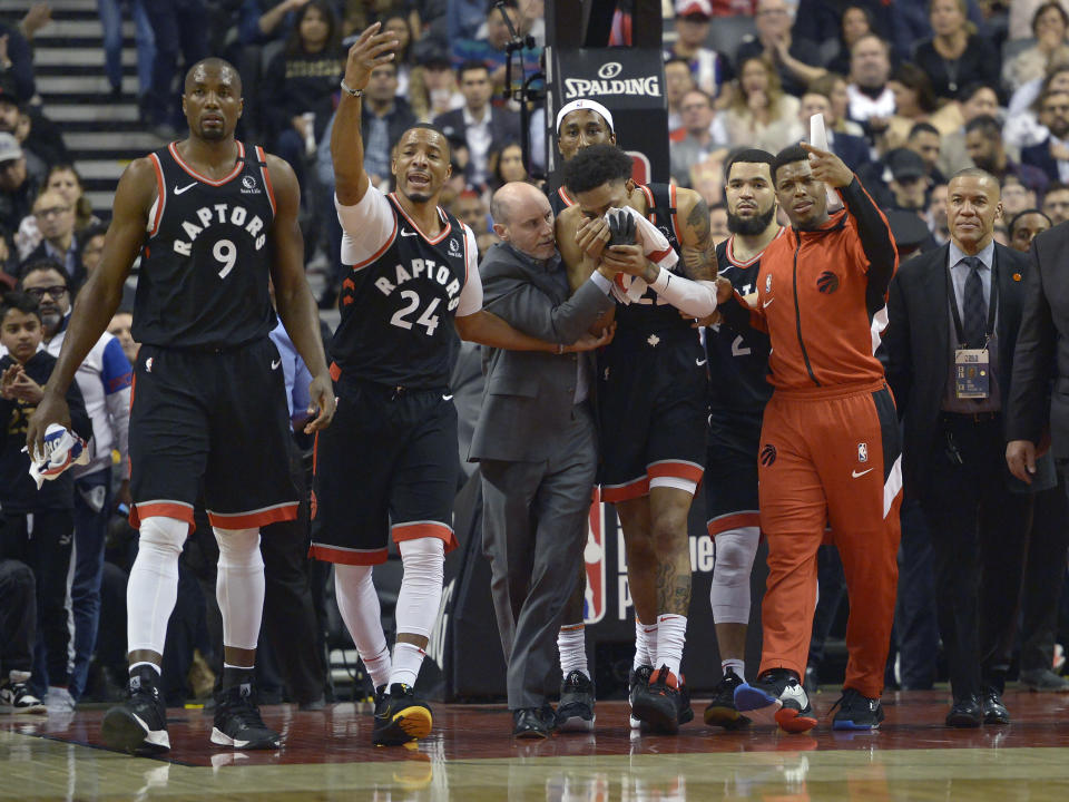 Toronto Raptors guard Patrick McCaw (22) leaves the court with help from players and staff after an injury during the first half of an NBA basketball game against the Philadelphia 76ers, Wednesday, Jan. 22, 2020 in Toronto. (Nathan Denette/The Canadian Press via AP)