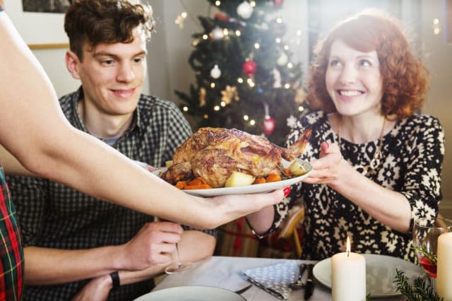 Woman takes plate with turkey at Christmas dinner.