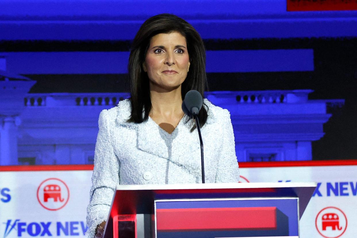 Nikki Haley smiles behind her microphone/podium on stage.