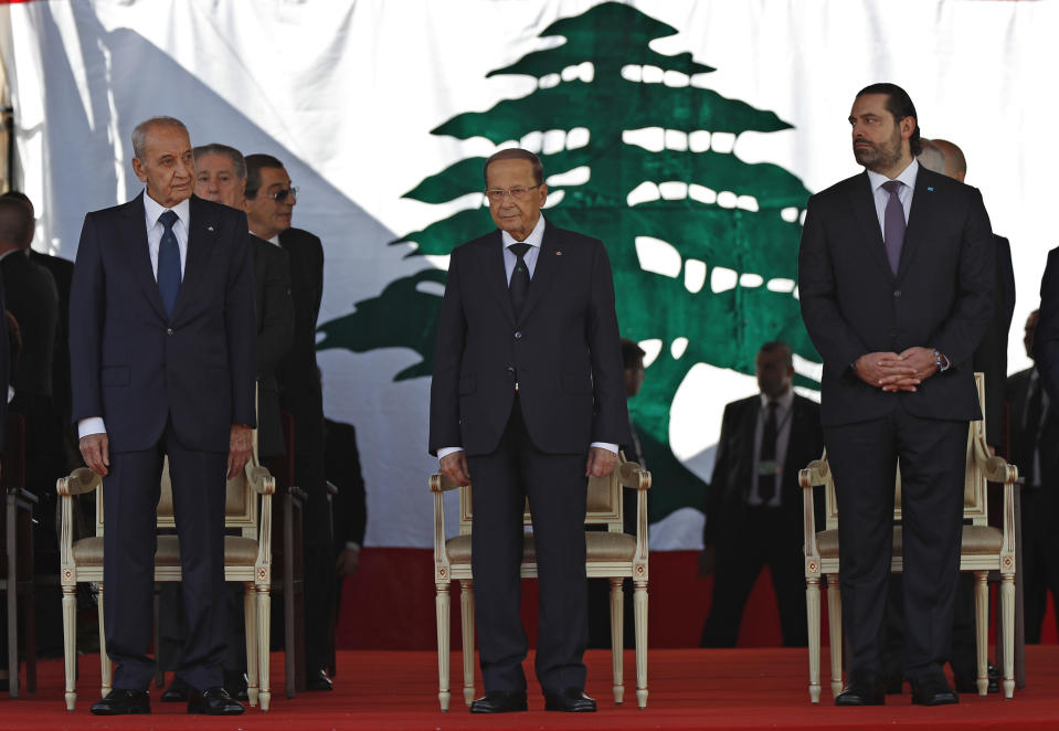 FILE -- In this November 22, 2018 file photo, Lebanese President Michel Aoun, center, Lebanese Prime Minister Saad Hariri, right, and Lebanese Parliament Speaker Nabih Berri, left, attend a military parade to mark the 75th anniversary of Lebanon's independence from France, in downtown Beirut, Lebanon. An Arab economic development summit that Lebanon is hosting this in Jan. 2018 has been marred by controversy days before delegates arrive. The turmoil is nothing new to Lebanon, a country fragmented along political fault lines. (AP Photo/Hussein Malla, File)