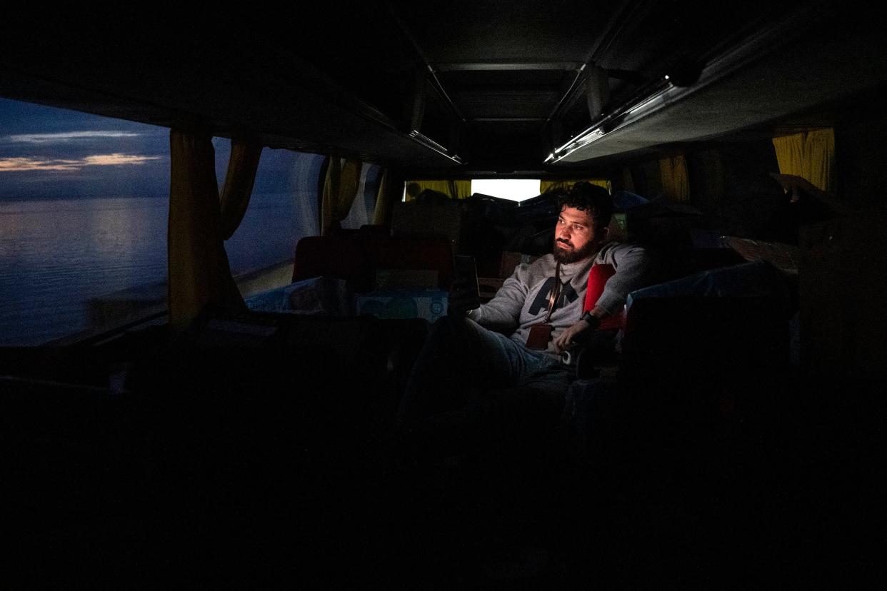 Salam Alzeen sits among aid supplies on a bus as he leaves Chernihiv, Ukraine, with only six evacuees after Russian forces retreated on April 7, 2022. The two buses and three Sprinter vans he organized were to be filled with people, but many decided to stay, feeling the war was over or evacuated earlier in the day. This story was produced in partnership with the Pulitzer Center.