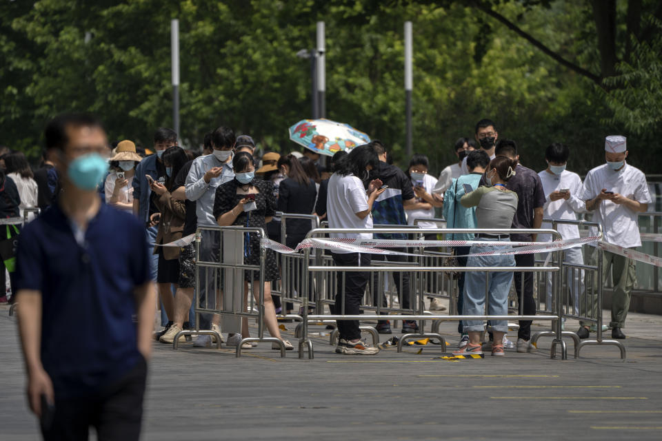 People stand in line for COVID-19 tests at a coronavirus testing site in Beijing, Thursday, May 19, 2022. Parts of Beijing on Thursday halted daily mass testing that had been conducted over the past several weeks, but many testing sites remained busy due to requirements for a negative COVID test in the last 48 hours to enter some buildings in China's capital. (AP Photo/Mark Schiefelbein)