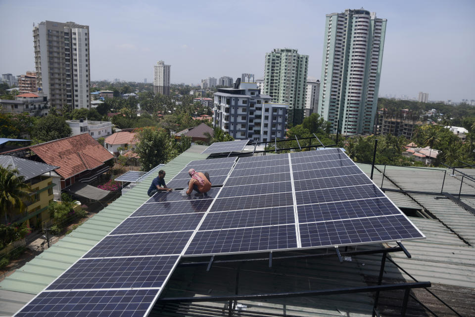 FILE - Workers install solar panels on the roof of a residential apartment in Kochi, southern Kerala state, India, March 22, 2023. The Indian government will not consider any proposals for new coal plants for the next five years and focus on growing its renewables sector, according to an updated national electricity plan released Wednesday evening. (AP Photo/R S Iyer, File)