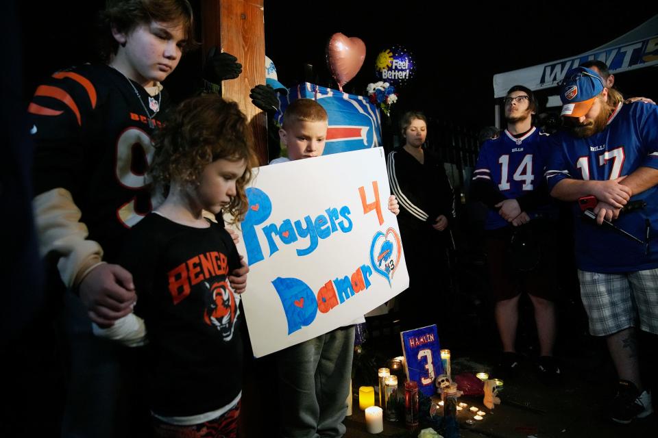 Brody Bennett, 13, left, stands with his sister Cameron Wilburn, 6, and brother, Tatem Wilburn 8, of Bellevue, Ky. as football fans pause for a moment of silence during a vigil for Buffalo Bills safety Damar Hamlin Jan. 3, 2023. The vigil was held outside of the University of Cincinnati Medical Center at 8:55 p.m., 24 hours after Hamlin collapsed during the Monday Night Football game with the Bengals.