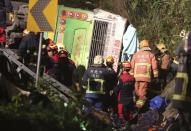 Members of rescue team at the scene where a bus collided with a car on a highway in Taipei, Taiwan, Monday, Feb. 13, 2017. A tour bus has flipped over on a highway near Taiwan's capital, killing over 30 people and trapping many others, officials said. (AP Photo)