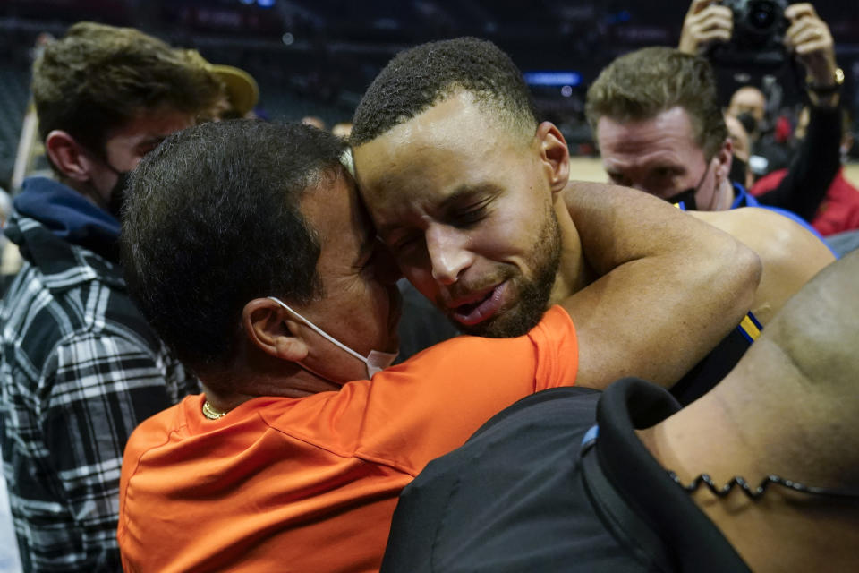 Golden State Warriors guard Stephen Curry, right, gets a hug from a fan after winning an NBA basketball game against the Los Angeles Clippers 105-90 in Los Angeles, Sunday, Nov. 28, 2021. (AP Photo/Ashley Landis)