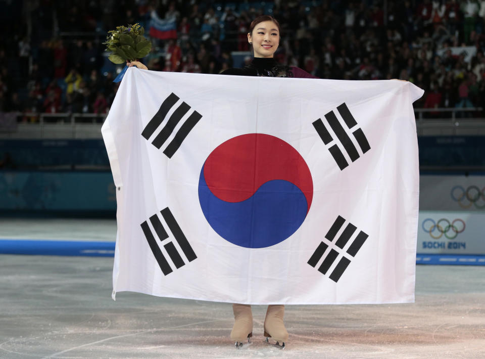 Yuna Kim of South Korea poses with the national flag as she celebrates her second place for the women's free skate figure skating final at the Iceberg Skating Palace during the 2014 Winter Olympics, Thursday, Feb. 20, 2014, in Sochi, Russia. Sotnikova placed first, followed by Kim and Kostner. (AP Photo/Ivan Sekretarev)