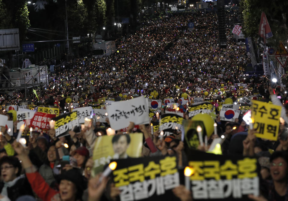 In this Saturday, Oct. 12, 2019, file photo, pro-government supporters hold candles during a rally supporting Justice Minister Cho Kuk in front of Seoul Central District Prosecutors' Office in Seoul, South Korea. Tens of thousands of government supporters gathered in South Korea's capital for the fourth straight Saturday to show their support for President Moon Jae-in's justice minister, who is enmeshed in an explosive political scandal that has polarized the nation. The letters read "Reform the Prosecution" and "Protect Cho Kuk." (AP Photo/Lee Jin-man, File)