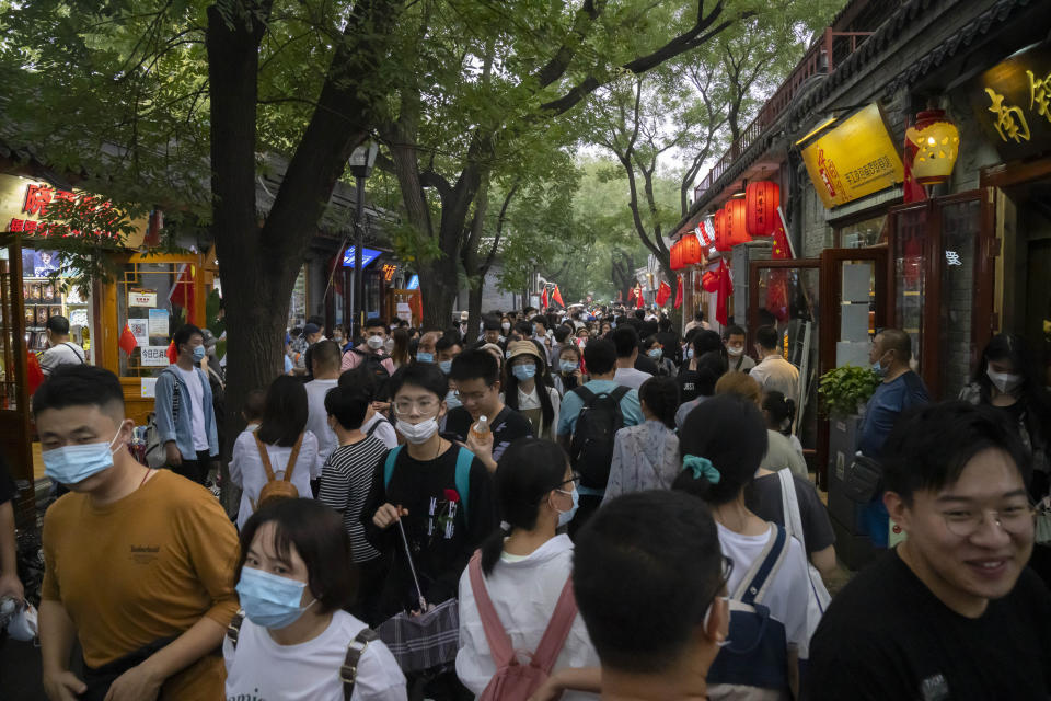 Crowds walk along a tourist shopping street on the first day of the National Day holiday period in Beijing, Saturday, Oct. 1, 2022. National Day marks the anniversary of the Oct. 1, 1949, founding of the People's Republic of China by then-leader Mao Zedong following a civil war. The mainland's former ruling Nationalist Party left for Taiwan, now a self-ruled democracy. (AP Photo/Mark Schiefelbein)