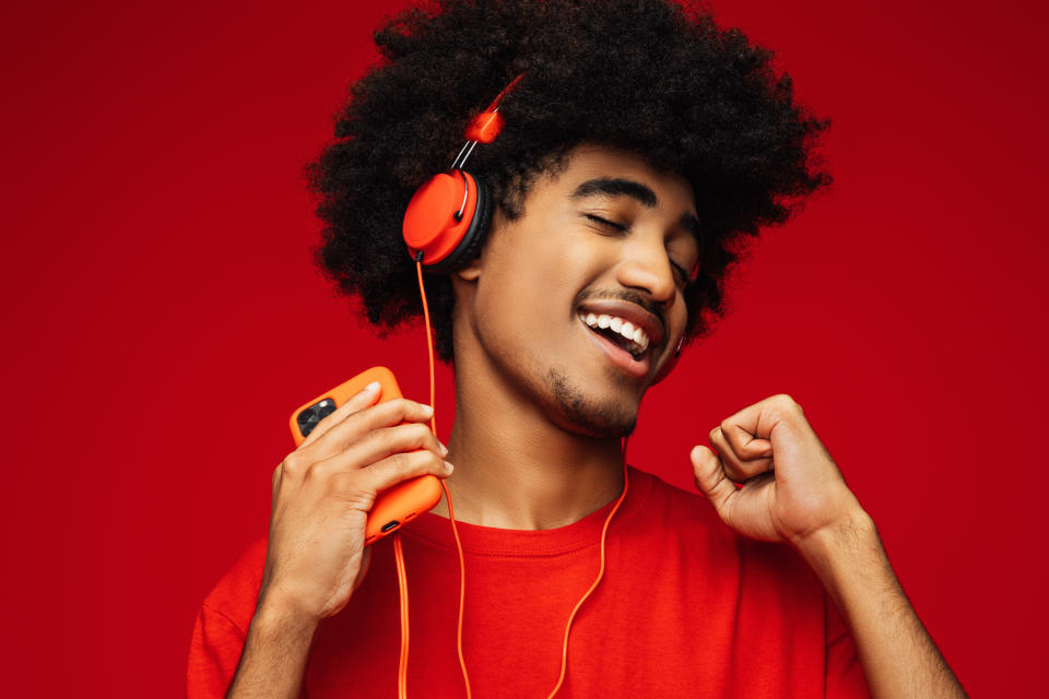 Young man in red shirt with red headphones dancing to music