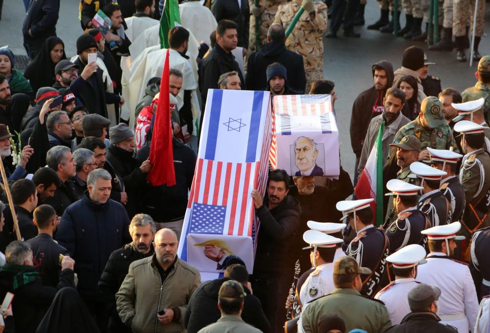 Mourners carry mock coffins with images of US President Donald Trump and Israeli Prime Minister Benjamin Netanyahu pasted on them as they gather to pay homage to slain Iranian military commander Qasem Soleimani, Iraqi paramilitary chief Abu Mahdi al-Muhandis and other victims of a US attack, in the capital Tehran on January 6, 2020. - Mourners packed the streets of Tehran for ceremonies to pay homage to Soleimani, who spearheaded Iran's Middle East operations as commander of the Revolutionary Guards' Quds Force and was killed in a US drone strike on January 3 near Baghdad airport. (Photo by Atta KENARE / AFP) (Photo by ATTA KENARE/AFP via Getty Images)